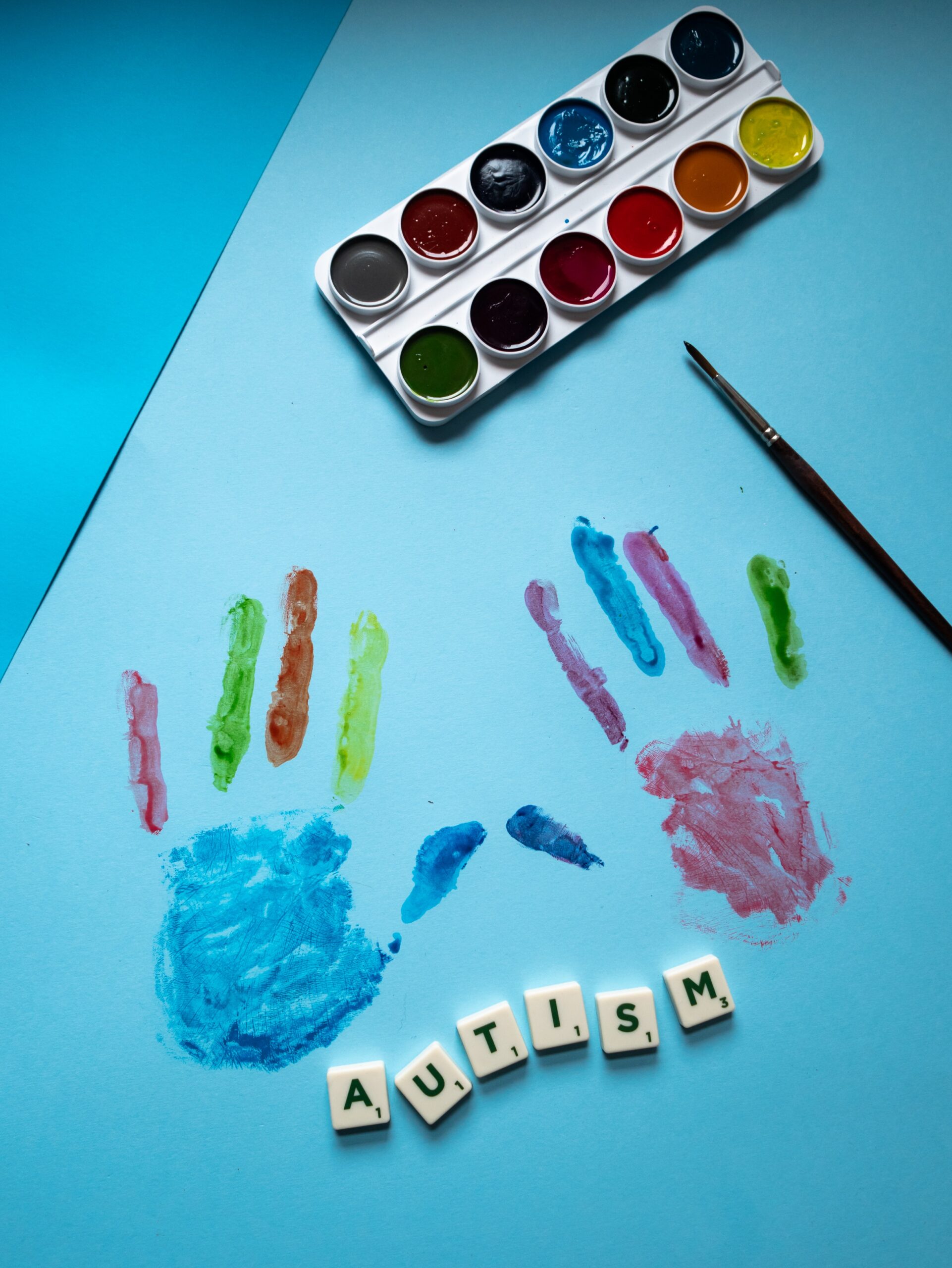 hands printed with multicolored paint and letters spelling out Autism